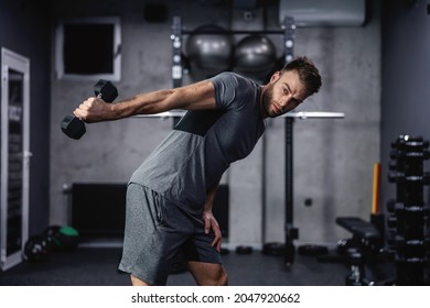 A seductive look of a sporty man with a beautiful face and handsome body. A photo of half a man's body during individual training in the modern gym. Arm and back exercises, sport lover