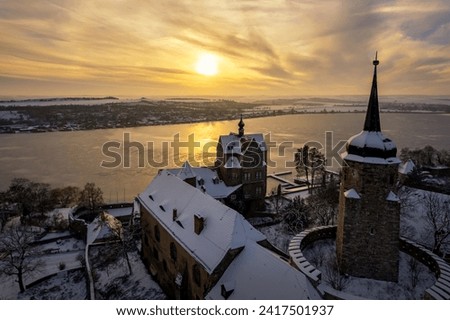 Seeburg Castle in winter with a view of Lake Sweet Lake at sunset