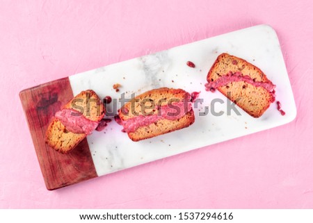 A seed cake with ruby chocolate, shot from the top on a pink background with a place for text