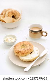 Seeded bagels with cream cheese and coffee in vertical format.  Healthy nutritious breakfast.