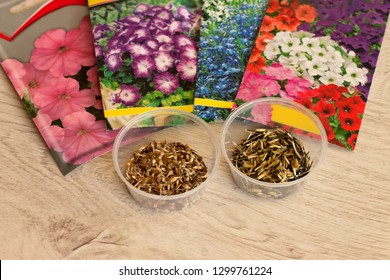 Seeds of annual flowers in bags and in bulk in jars lie on a woodensurface