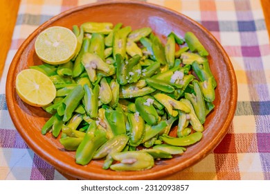 Seeds of Inga edulis, exotic fruit served in a clay dish accompanied by lemon and salt. commonly called: guama, guaba, pacae or pacay - Shutterstock ID 2312093857