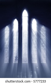 Seeing the light, shafts of light stream through stained glass window and onto cross below