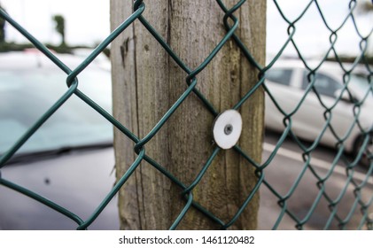 Seeing A Parking Lot Through A Chain-link Fencing. Type Of Woven Fence Usually Made From Galvanized Or LLDPE-coated Steel Wire, Zig-zag Pattern.