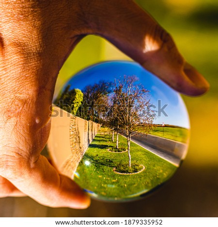 Seeing the road flipped upside down through a photography lens ball held by a hand