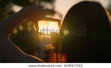 Seeing world as different Concept. Sees like in movies. Hands of a young female director cameraman making frame gesture at sunset. Business planning. Girl shows her fingers frame symbol in sun.