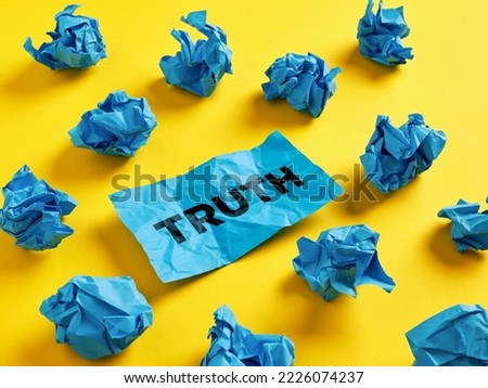 Seeking, revealing or finding the truth in tangled information. The word truth on piece of paper among the crumpled blue paper balls.