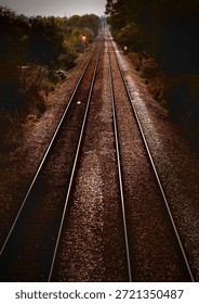 Seemingly endless train line heading into wooded horizon