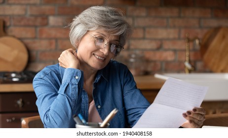 It seems interesting. Focused elderly latin woman engaged in reading commercial offer in letter from bank think on good loan terms conditions. Concentrated old lady in glasses do paperwork check bills