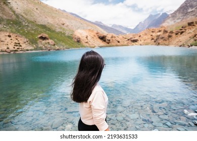 Seen from behind Beautiful Indian tourist woman standing against Deepak Tal lake in front of Himalayan mountains at Himachal Pradesh, India. Mountain landscape, glacier lake and mountain range