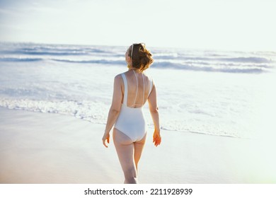 Seen From Behind Elegant 40 Years Old Woman In White Swimwear At The Beach Relaxing.