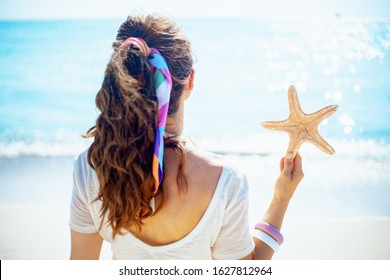 Seen From Behind Healthy 40 Year Old Woman In White T-shirt With Starfish On The Beach.