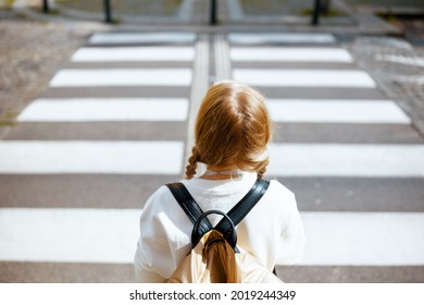 Seen From Behind Modern Child In White Sweatshirt With Backpack Crossing Crosswalk And Going To School Outdoors In The City.