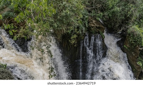 Seething streams of water flow down from the rocks among lush green vegetation. Close-up. Iguazu Falls. Argentina. Fragment of a waterfall. - Shutterstock ID 2364942719