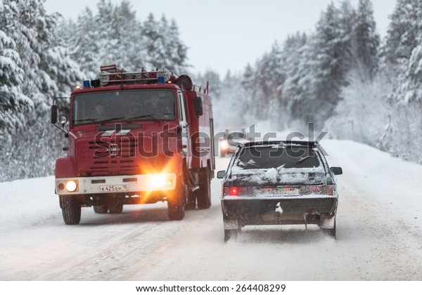 SEGEZHA, KARELIA, RUSSIA\
- CIRCA DEC, 2014: fire fighting truck and cars are on the Kola\
highway in winter season. The Kola is a federal road from St.\
Petersburg to Murmansk