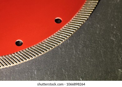 Segment of a diamond red disc for cutting against a gray granite background close-up.