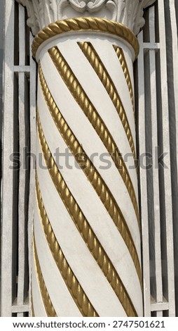 Segment of a stylish architectural pillar showcasing striking gold rope patterns spiraling beautifully on a pristine white column.