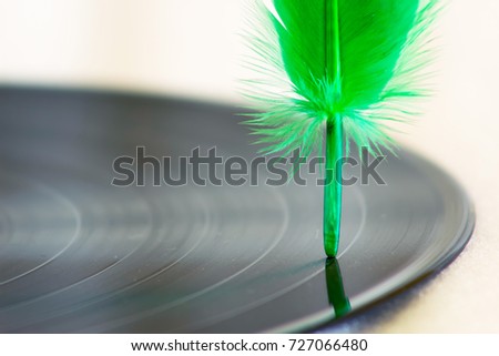 Segment of vinyl record with Old feather.Writing music.
