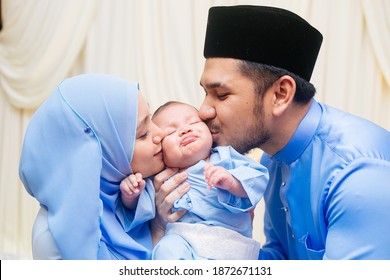 SELANGOR - JULY 24 2017: Muslim Husband And Wife Wearing Malay Tradisional Clothes And Kissed Baby On His Cheeks