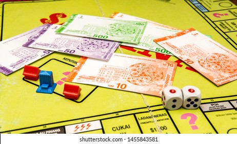 Selangor, Malaysia - July 19, 2019: Fakes money/currency, two dices and mini house miniature on the Saidina board game, a property trading game and is a household name in Malaysia.