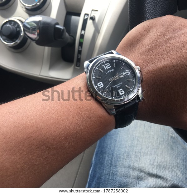 Selangor State, Malaysia, 31.07.2020: A young man\
styled a Casio brand watch while in the car while waiting for the\
green light signal to turn\
on.