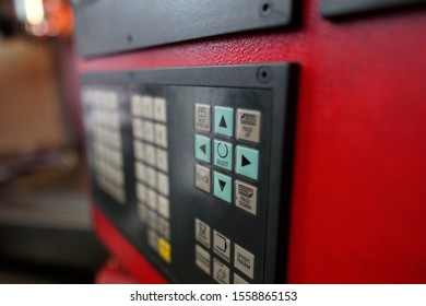 select button focused on the keypad of a control panel of CNC machine in a metal machining workshop
