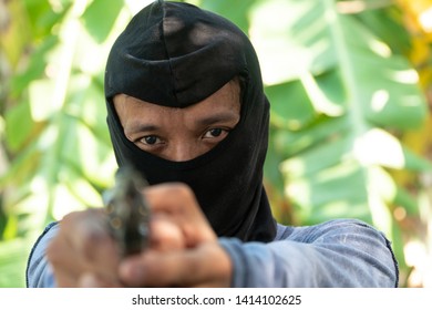 Select Focus Of Crime Eyes. Robber In Black Ski Mask Aims With Gun