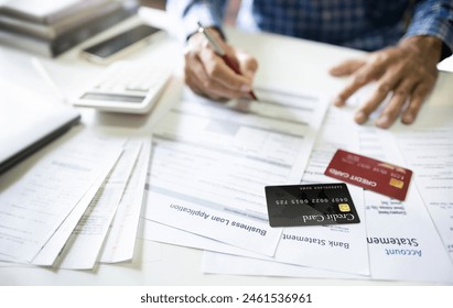 Select focus on credit card witn personal loan documents and bank statement used to apply for a personal loan and a man reviewing contract befor sign to apply financial loan - Powered by Shutterstock