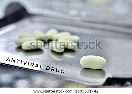 Select focus photo of yellow tablet on tray are medicine dispensing by pharmacist. antiviral drug with text(Antiviral drug) on picture