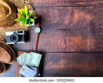 Select focus. Top view of accessories for tourist to travel in Brown tone on Travel concept, Camera on notebook and airplane with passport and money and outfit and shoes on wooden background.