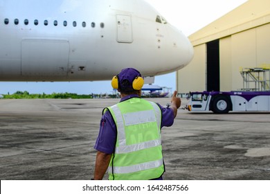 Selected focus at Aircraft mechanic use finger sign thumb up during Aircraft towing tractors towing aircraft (airplane) out from aircraft hangar after finished maintenance.