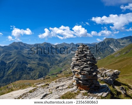 Selected focus of cairns of stones with scenic view of mountain landscape with a rocky terrain near Castelmagno, Valle Grana, province of Cuneo, Piedmont, Italy. Blue sky with a few fluffy clouds
