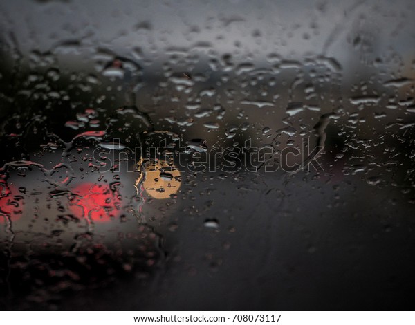 Selected focus drop of water on the
glass outside the car in the raining day. Blur
background.