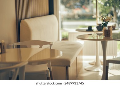 Selected focus: an empty glass table against the background of a coffee shop or restaurant window with a bokeh effect. White leather sofa for relaxing. High quality photo