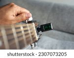 Selected focus photo of someone tuning guitar with digital guitar tuner.                                              