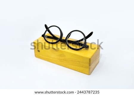 Selected focus photo of wooden frame glasses on golden yellow wooden box on white background