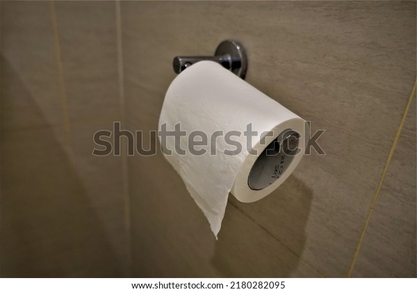 Selected focus tissue paper hanging on a bracket\
on a ceramic wall in the\
toilet