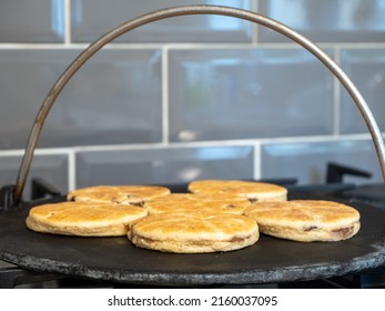 selected focus Welsh Cakes cooking on a cast iron griddle over a gas hob flame