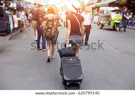 Selected focus young woman traveller with travel luggage walking on street in Khao San road in Thailand