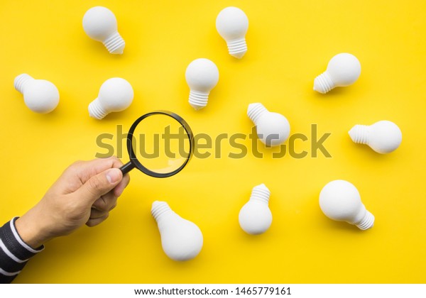 Selected great ideas\
concepts with male hand using magnifying glass looking for group of\
lightbulb on color background.Business creativity.human\
performance