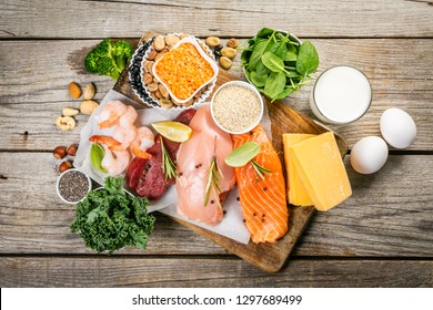 Selection Of Animal And Plant Protein Sources - Fish, Meat, Beans, Cheese, Eggs, Nuts And Seeds, Kale, On Wood Background