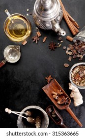 Selection Of Aromatic Spices And Crystallised Sugar For Making Spicy Tea For A Winter Beverage Viewed From Above With A Teapot And Cup Of Hot Tea Over Black With Copyspace