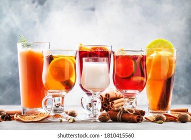 Selection Of Autumn Or Winter Alcoholic Hot Drinks And Cocktails - Mulled Wine, Glogg, Grog, Eggnog, Warm Ginger Ale, Hot Buttered Rum, Punch, Mulled Apple Cider On Gray Background, Copy Space