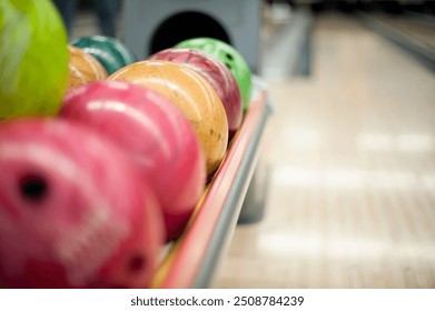 A selection of brightly colored bowling balls lined up in a rack, ready for a game at the bowling alley. 