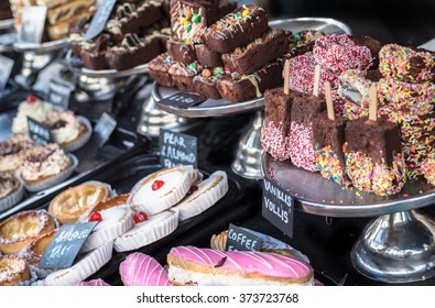 A selection of cakes and chocolate brownies for sale.
