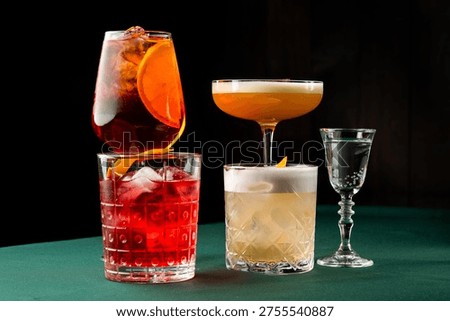 A selection of classic alcoholic cocktails, including a Negroni, Aperol Spritz, and Whiskey Sour, presented on a dark green table against a black background