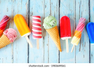 Selection of colorful summer popsicles and ice cream treats. Overhead view scattered on a rustic blue background.