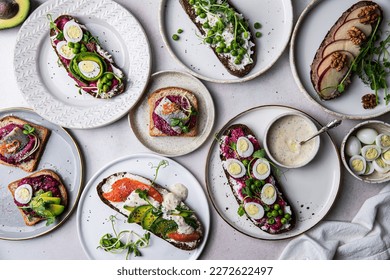 Selection of ``Danish smorrebrod - open-faced sandwiches with different toppings: avocado, quail eggs, salmon, beetroot paste, pickled herring, green pea, cream cheese etc. - Powered by Shutterstock