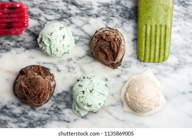 Selection of different ice cream scoops such as mint, chocolate and strawberry on marble background, top view