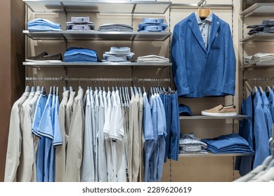 A selection of elegant business men's clothing on hangers in a store. Shirts, jackets and T-shirts on hangers. Style and fashion. Front view. - Powered by Shutterstock